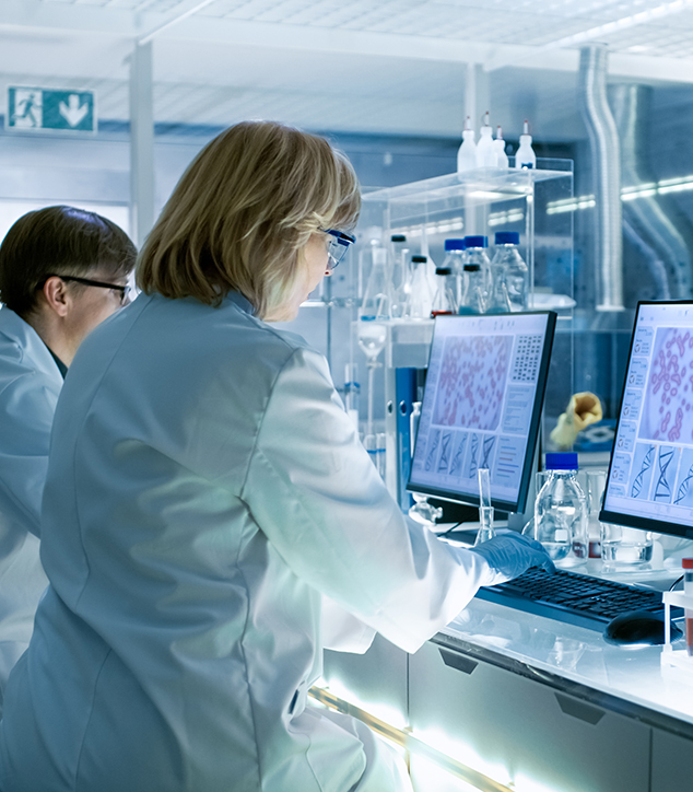 Scientists analyzing cell and DNA imagery on computers in a research lab.